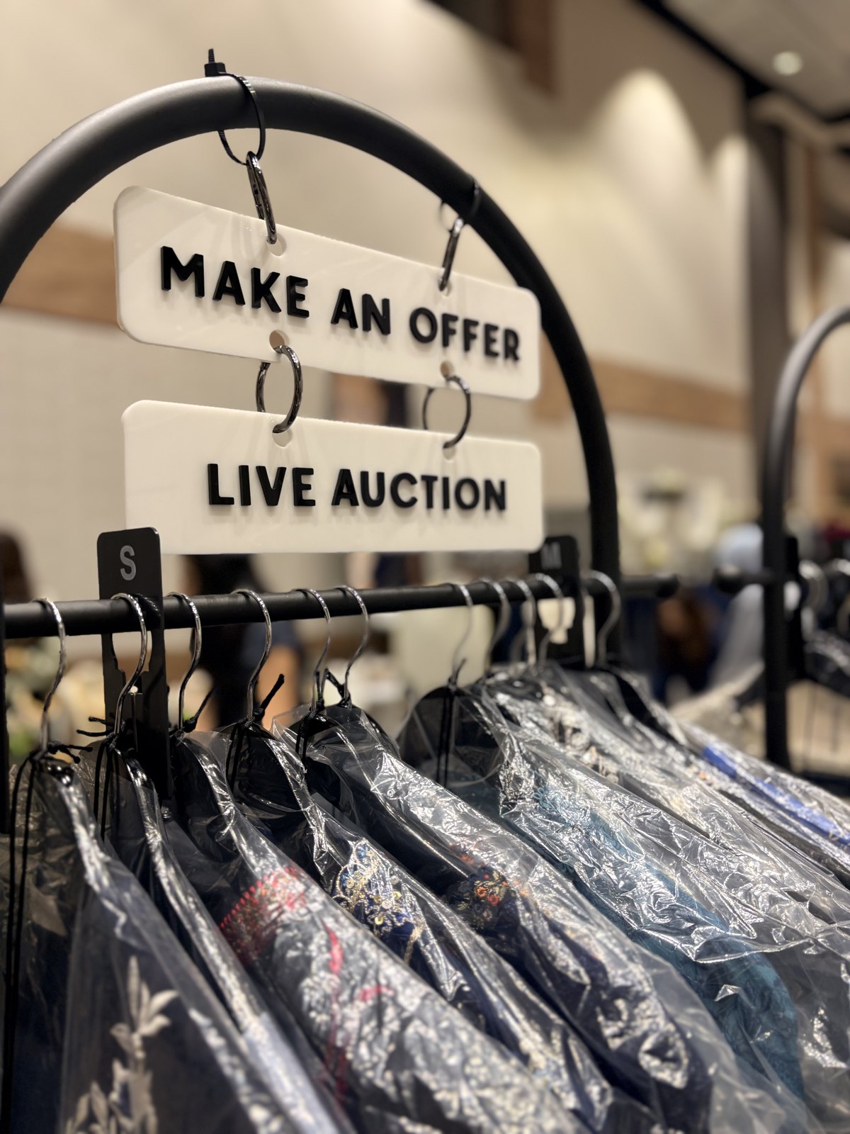 Clothing rack at the pop-up with 'Make an offer' and 'Live auction' signs